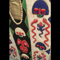 1950s Yoruba ceremonial beaded tunic with animal motifs and abstract patterns, displayed on a metal stand.