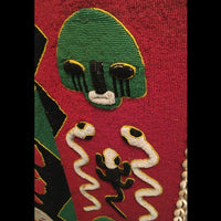 1950s Yoruba ceremonial beaded tunic with animal motifs and abstract patterns, displayed on a metal stand.